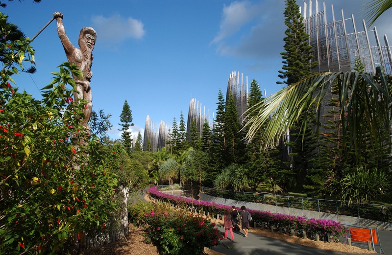 Personnes qui entrent au Centre Culturel Djibaou à Nouméa dont l'architecture se mêle parfaitement au paysage
